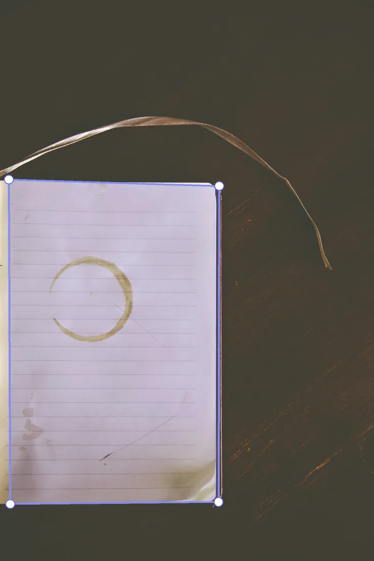 Before: Notebook on a dark desk with the page outline the model detected drawn over it